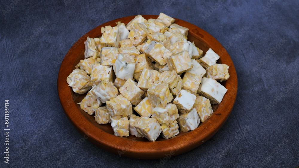raw tempeh cut into pieces on a wooden plate raw tempeh cut into pieces on a wooden plate
