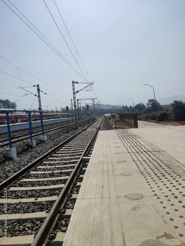 Fototapeta premium Empty train station platform with tracks, no visible people.