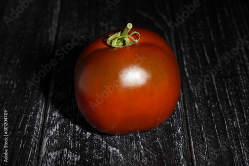 kumato tomato on black wood background photo