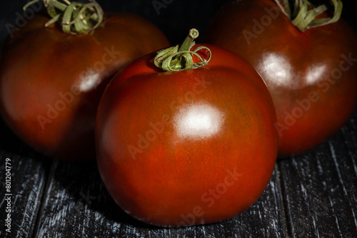 kumato tomato on black wood background © bergamont