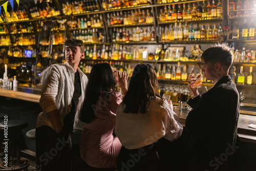 Man tired of bored fiends company looks aside in cozy bar. Group of young people spends time together at party in night club
