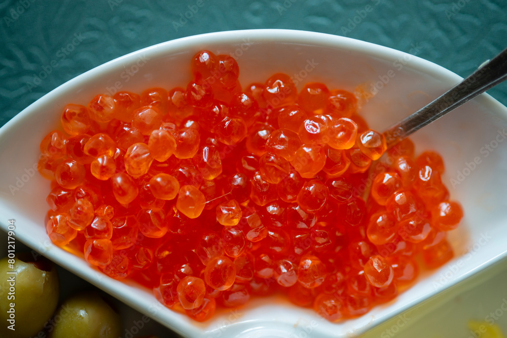 Red caviar in a white plate with olives, cheese and spoon Red caviar in a white plate with olives, cheese and spoon