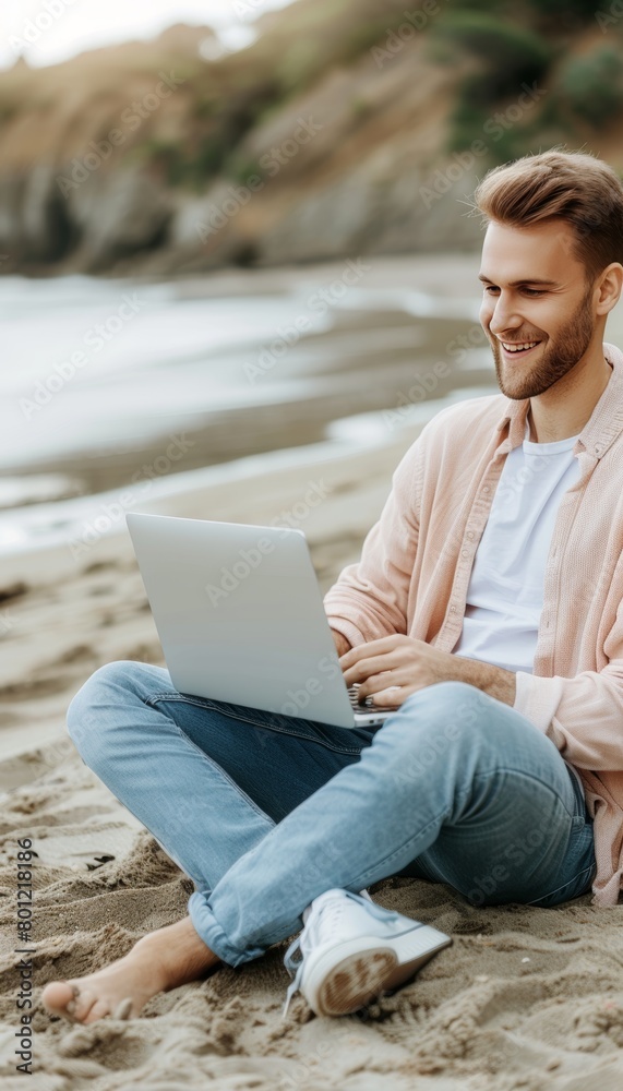 Young man in casual attire working remotely on laptop at the beach, freelancing lifestyle