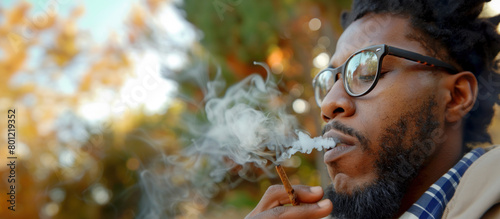 Black man smoking marijuana or cigarette outdoors