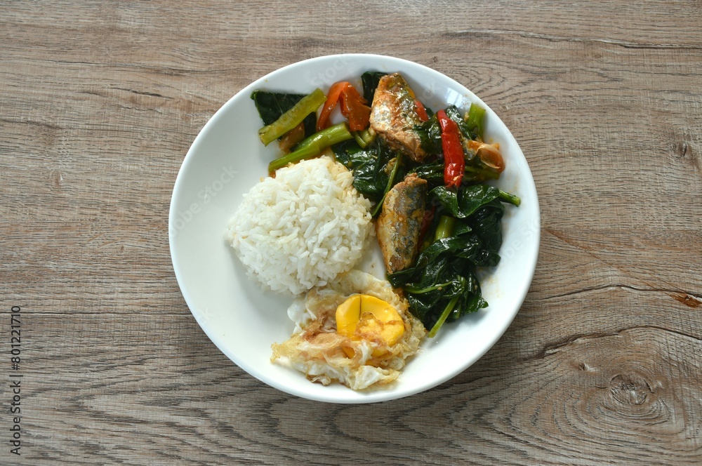 spicy stir fried Chinese kale with fish can in tomato sauce topping egg on rice spicy stir fried Chinese kale with fish can in tomato sauce topping egg on rice