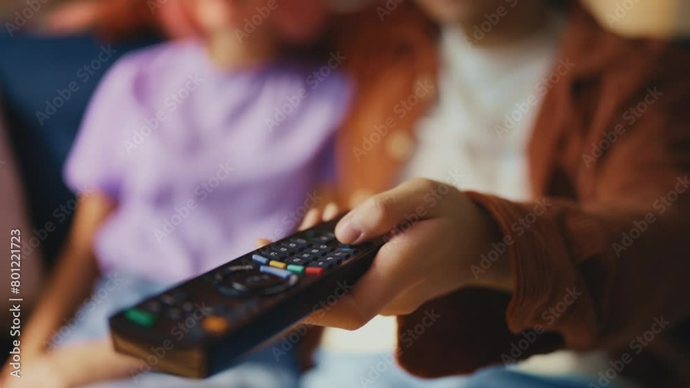 Young man switching TV channels using remote control, couple watching a movie