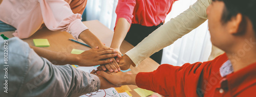 A group of business people putting their hands together at meeting room on table with mind map scatter around. Startup group showing unity teamwork and friendship. Close up. Focus on hand. Variegated.