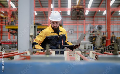 Industrial engineer in safety helmet uniform jacket working in heavy steel engineering factory. Technician manager worker inspector using laptop in metalwork product manufacturing facility workplace