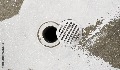 Rain water puddle flood flowing into small round outdoor street metal drain gutter sewage water way with opened lid isolated footage on horizontal ratio background. photo