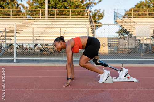 Paralympic athlete with prosthetic leg waiting to take off on sprint starting blocks photo
