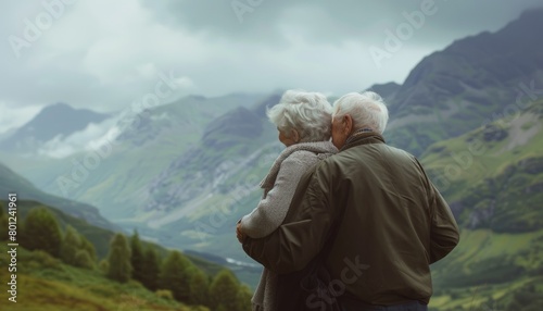 Elderly couple cuddling while looking at mountains