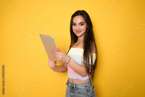 Smart intelligent caucasian hispanic latin-american young woman student using digital tablet isolated over yellow background.