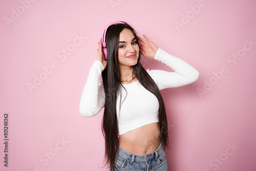 smiling attractive woman listening to music in headphones on pink background photo
