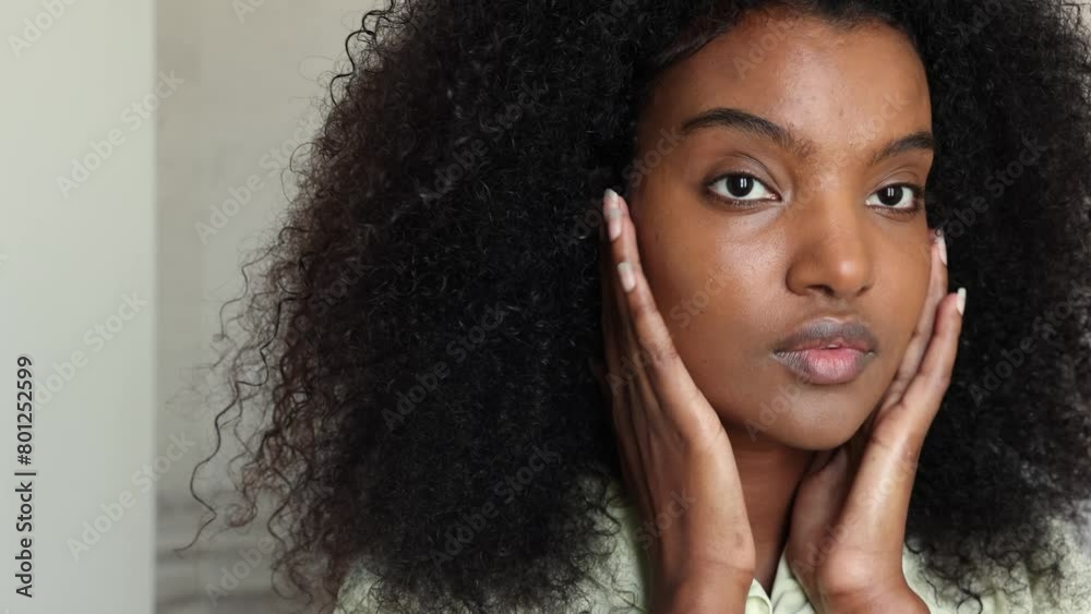A pretty black afro African American woman gentle massage her face after putting sunscreen A pretty black afro African American woman gentle massage her face after putting sunscreen