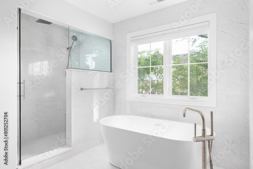 A beautiful bathroom s freestanding tub with a bronze faucet and marble lined walk-in shower. No brands or labels.