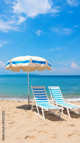 Two beach chairs under a beach umbrella on a sandy beach with the ocean in the background