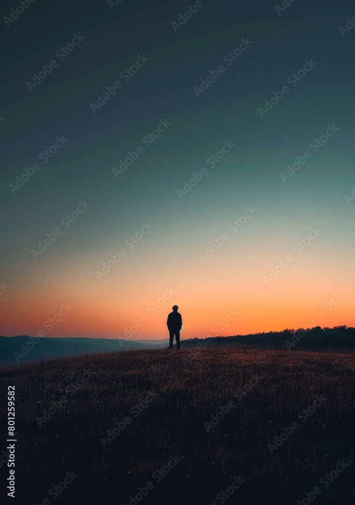 Man standing alone on a hill during sunset