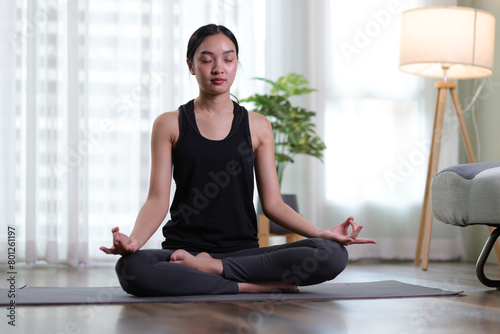 Beautiful asian woman doing relaxing exercise at home and practicing yoga in quiet living room.