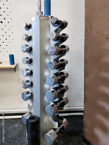 dumbbells with different weights on a rack in the gym