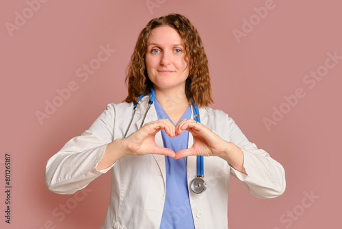 Woman doctor heart gesture, studio pink background. Nurse in uniform with stethoscope on red studio background © Андрей Журавлев
