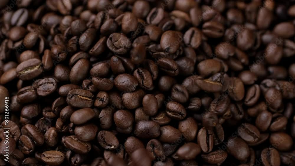 Dark roast coffee beans falling down on heap, top view Dark roast coffee beans falling down on heap, top view