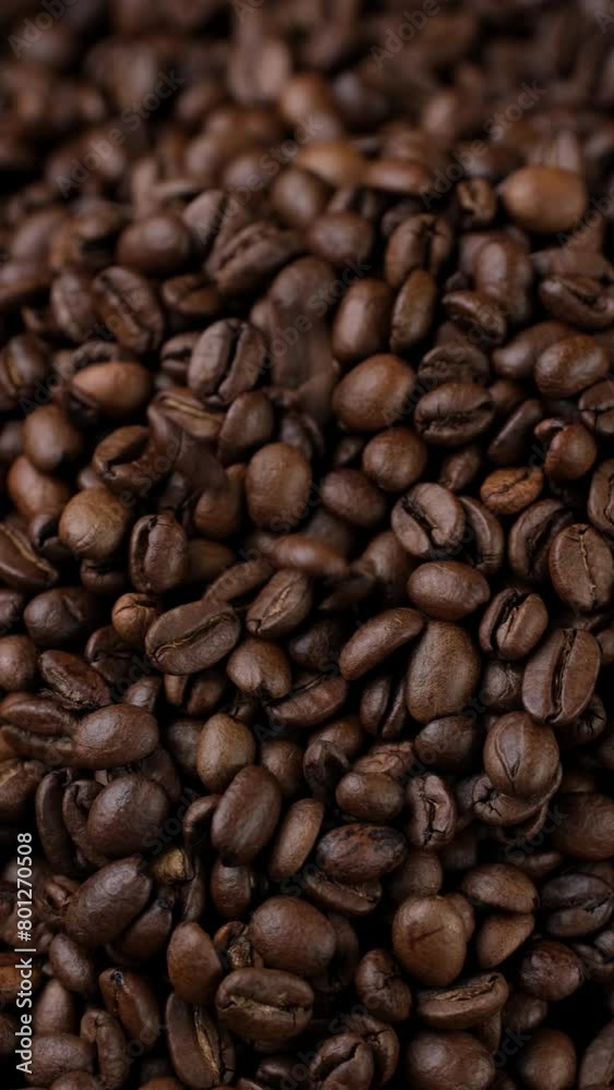 Dark roast coffee beans falling down on heap Dark roast coffee beans falling down on heap