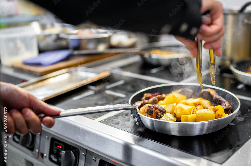 A skilled chef expertly cooks diced potatoes and meat in a sizzling frying pan, showcasing culinary artistry
