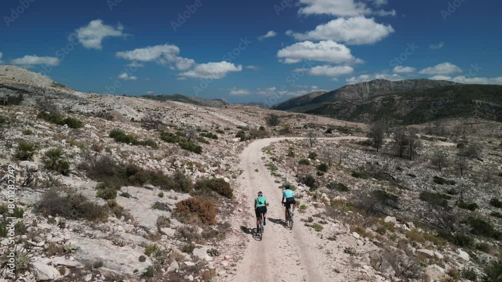Drone view of cyclists riding gravel bikes in the scenic beauty of the mountains. Cycling on gravel roads or off-road.Active adventures and the concept of travel by bike. Gravel bike riding in nature. Drone view of cyclists riding gravel bikes in the scenic beauty of the mountains. Cycling on gravel roads or off-road.Active adventures and the concept of travel by bike. Gravel bike riding in nature.