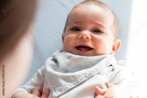 Baby boy smiling on bed while playing with mother. Closeup view on open mouth of baby. First teeth growing.