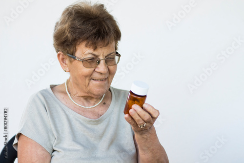 Mature woman in glasses hold bottle with pills read medicine instruction on packaging before take meds, senior female retiree in spectacles thinking of medication treatment