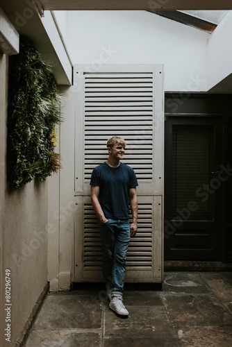 Man in blue tee standing in front of white door © Rawpixel.com