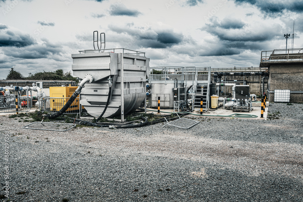 Recently upgraded sewage treatment plant showing remote control electronics used to control fluid flow in the material treatment plant. The large steel container is used to add chemicals. Recently upgraded sewage treatment plant showing remote control electronics used to control fluid flow in the material treatment plant. The large steel container is used to add chemicals.