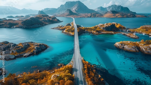 Aerial image features the majestic Saltstraumen Bridge in Norway, gracefully arching over turquoise waters, framed by vibrant autumn foliage and rugged mountains. photo
