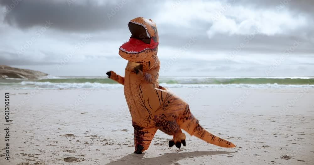 Comic, funny and dinosaur costume on beach dancing with energy for comedy joke on vacation travel. Goofy, silly and inflatable animal mascot moving, jumping and having fun by ocean on holiday.