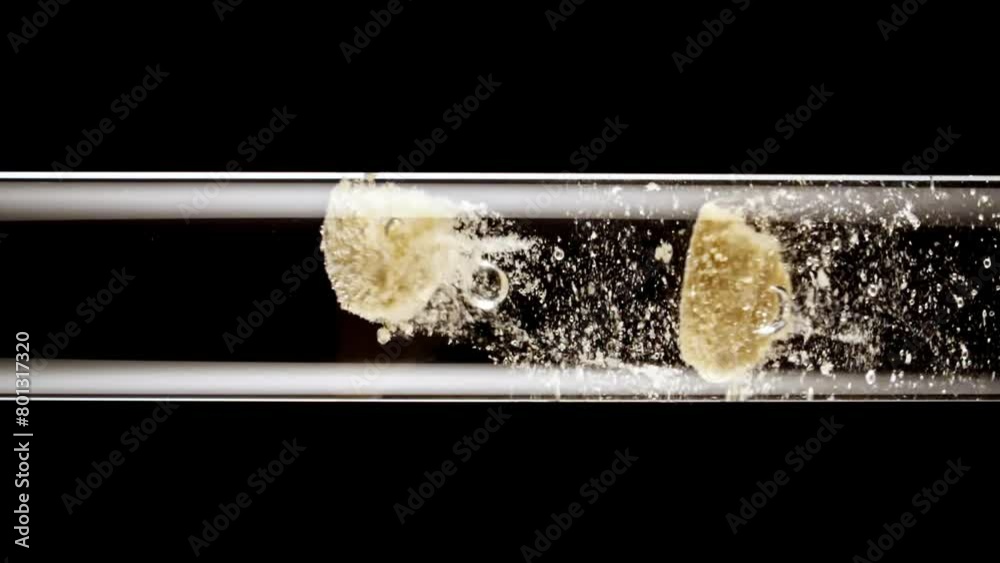Close up tablet of aspirin, vitamin falls into of water in glass test tube in slow motion on black background. Macro shot of bubbles effervescent. The medicine concept, health care, treatment.FullHD Close up tablet of aspirin, vitamin falls into of water in glass test tube in slow motion on black background. Macro shot of bubbles effervescent. The medicine concept, health care, treatment.FullHD