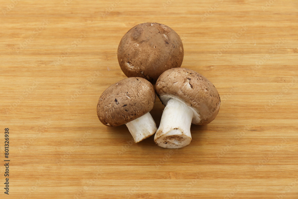 Fresh champignon mushroom isolated on wooden background Fresh champignon mushroom isolated on wooden background