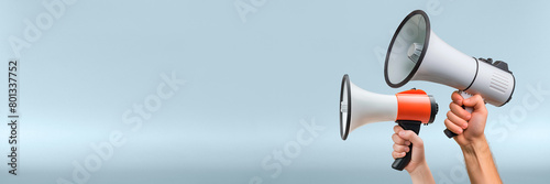 Hands holding megaphones on a solid blue background. Active communication and information dissemination, advertising messages and event announcements photo