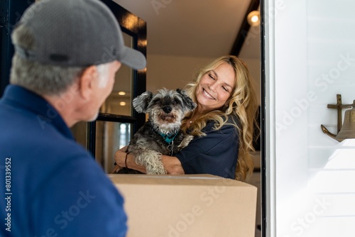 Woman receiving package delivery, holding a dog image photo