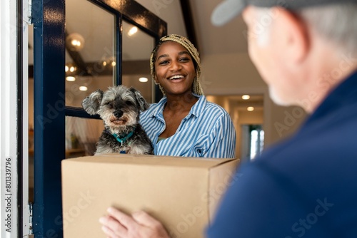 Black woman receiving package delivery, holding a dog image photo