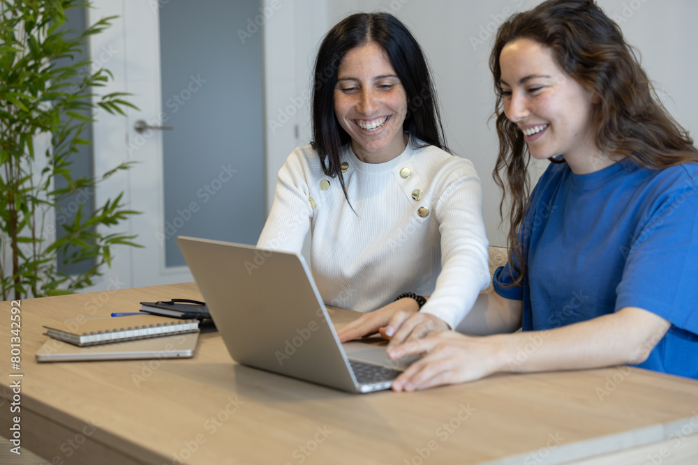 colleagues smiling while working from home with their laptop colleagues smiling while working from home with their laptop