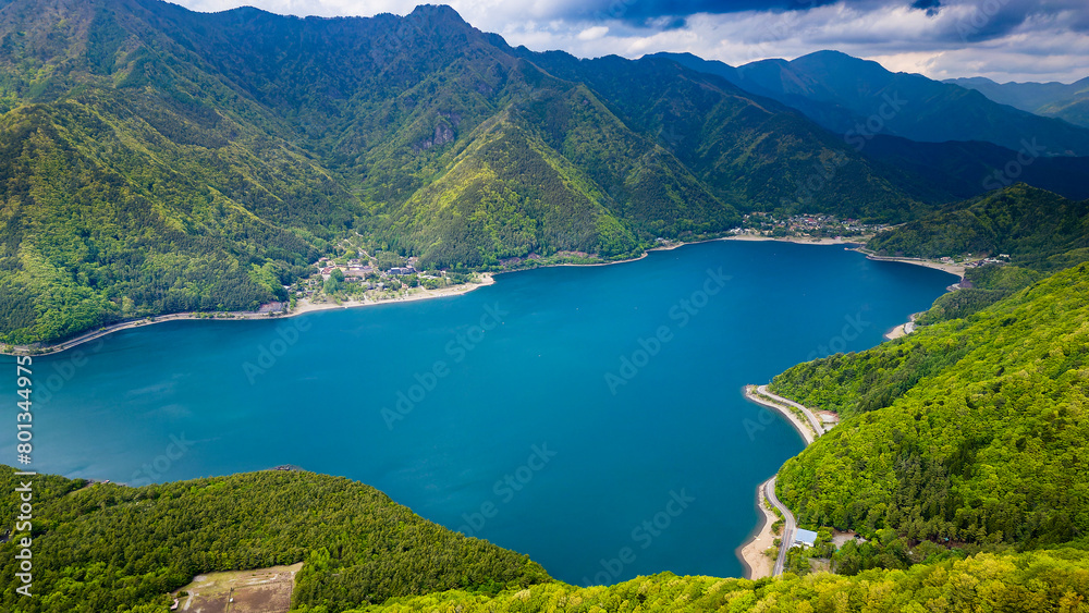 Aerial view of lush green forest surrounding a volcanic lake (Lake Saiko, Yamanashi, Japan)