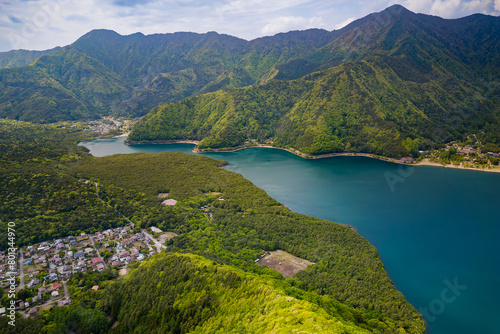 Aerial view of lush green forest surrounding a volcanic lake (Lake Saiko, Yamanashi, Japan)