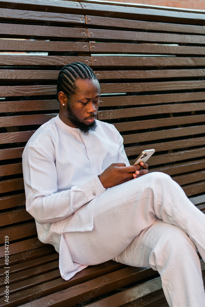 Fototapeta premium Millennial generation african american man typing sms outdoor 5g internet concept. High speed internet on phone and chatting on social networks and blog concept