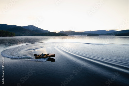 USA, New York, Lake Placid, Man in wooden boat on lake at sunrise photo