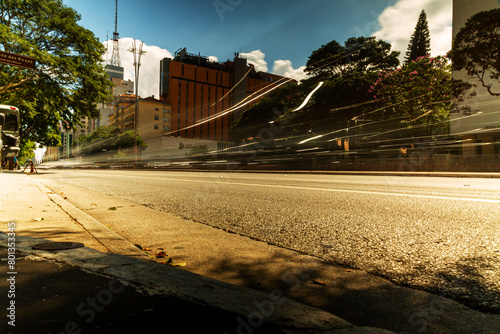 Avenida e rastro de luz dos faróis dos carros durante o dia.  photo