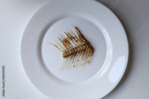 One Gourami fish bone, on white plate, isolated on white background, flat lay or top view photo