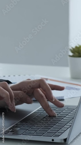 Close up of Indian female employee hands texting or typing on laptop keyboard in the office. Busy office worker concept. Vertical video. photo