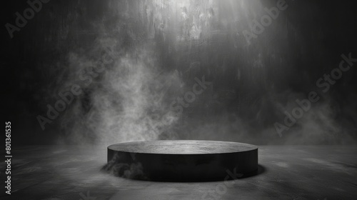 A spotlight shines down on a dark, concrete pedestal surrounded by smoke.