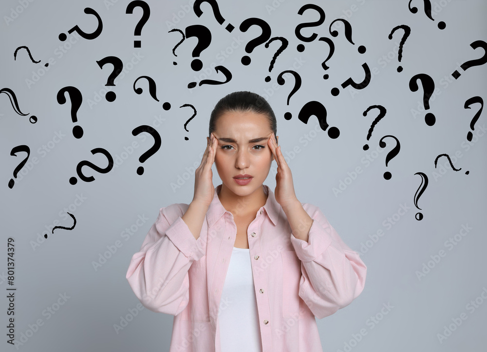 Amnesia. Confused young woman and question marks on light grey background Amnesia. Confused young woman and question marks on light grey background