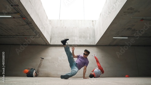 Group of stylish hipster perform dancing together in building. Happy break dancer enjoy moving to hip hop music with freestyle dance surrounded by street dancer team. Outdoor sport 2024. Sprightly.